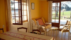 A dining area with a table set for two, a sofa, and two armchairs.