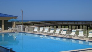 Una piscina amb gandules i un pont de fusta amb vista a l'oceà.