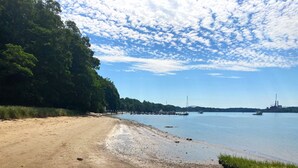A sandy beach with a calm body of water, a dock, and a bridge in the distance. - The Perfect Location to relax and explore all that the Seacoast has to offer!  (Eliot)