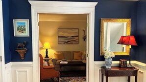 A hallway with a wooden floor, a sofa, a lamp, a mirror, and a framed picture on the wall. - The Perfect Location to relax and explore all that the Seacoast has to offer!  (Eliot)