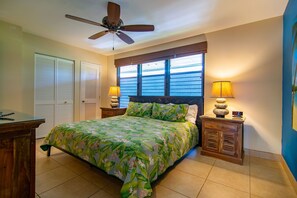 A bedroom with a bed, two nightstands, a ceiling fan, and a window with blinds.