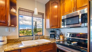 A kitchen with wooden cabinets, a double sink, a coffee maker, a microwave, and an oven.