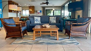 A modern living room with a sofa, two armchairs, a coffee table, and a ceiling fan.