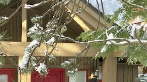 A house with a red door, a wreath, and a stack of firewood. - Spacious Rustic Whistler Retreat at the Woods (Whistler)