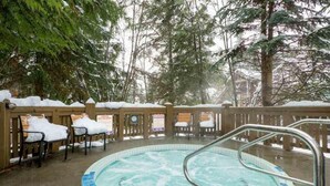 A hot tub area with a wooden deck, surrounded by snow-covered trees. - Spacious Rustic Whistler Retreat at the Woods (Whistler)