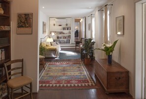 Un pasillo con alfombra estampada, muebles de madera y una estantería.