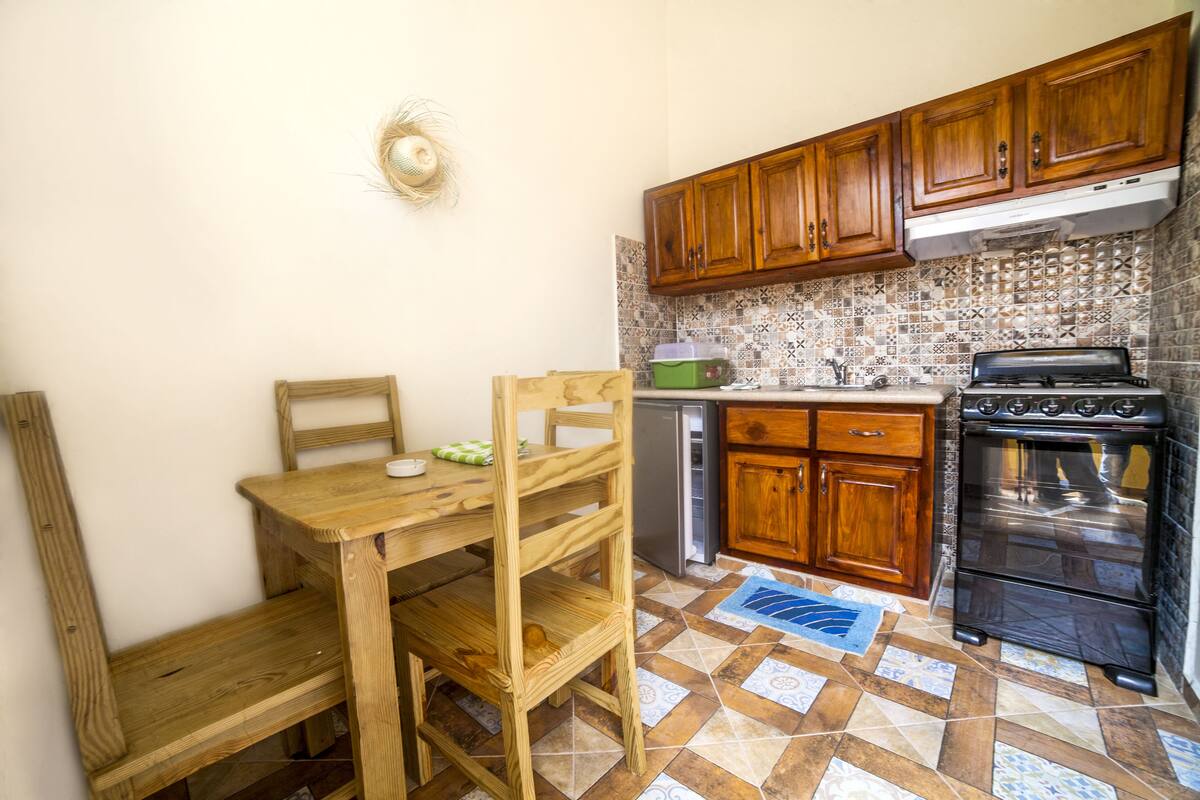 A compact kitchen with wooden cabinets, a built-in oven, and a small refrigerator.