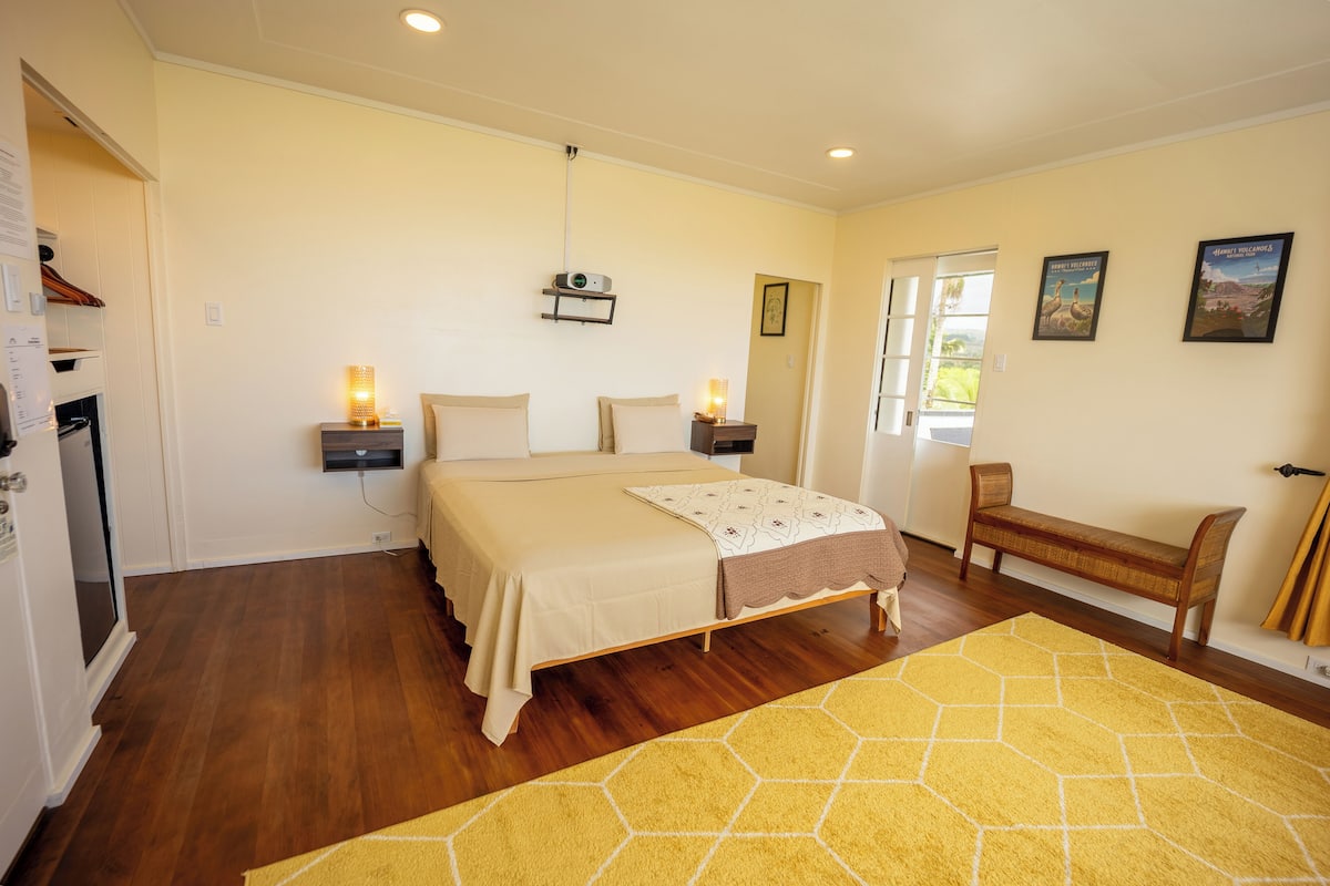 A bedroom with a bed, bedside lamps, a bench, and a window.