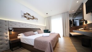 A modern hotel room with a large bed, a bedside table, a desk with a chair, a mirror, and a TV. - Hotel Scala dOro (Vodice)