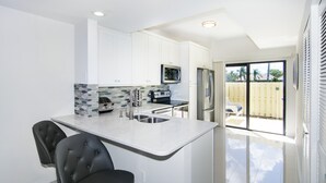 A modern kitchen with white cabinets, a microwave, a refrigerator, and a dining area with two chairs. - 1900 ft from beach Luxury Jupiter Beach Villa! private entrance community pool (Jupiter)