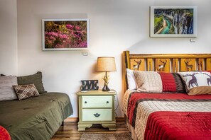 Un dormitorio con dos camas, una mesita de noche y dos cuadros en la pared.