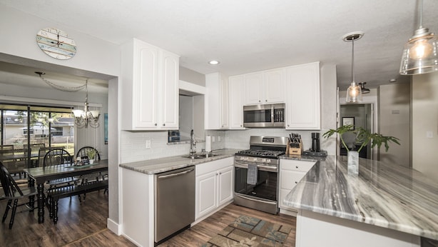 A modern kitchen with white cabinetry, stainless steel appliances, and a marble countertop. - Classy & Clean Pet Friendly (Clearwater)