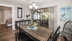 A dining area with a wooden table, chairs, a chandelier, and a large window with curtains. - Classy & Clean Pet Friendly (Clearwater)