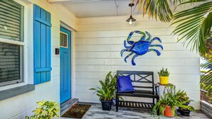 A porch with a blue door, a bench with a blue cushion, and several potted plants. - Classy & Clean Pet Friendly (Clearwater)