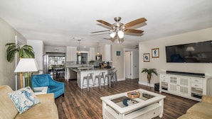 A modern living room with a ceiling fan, a kitchen area, and a dining space. - Classy & Clean Pet Friendly (Clearwater)