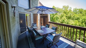Ein Balkon mit Esstisch, Gartenmöbeln und einem großen Sonnenschirm.