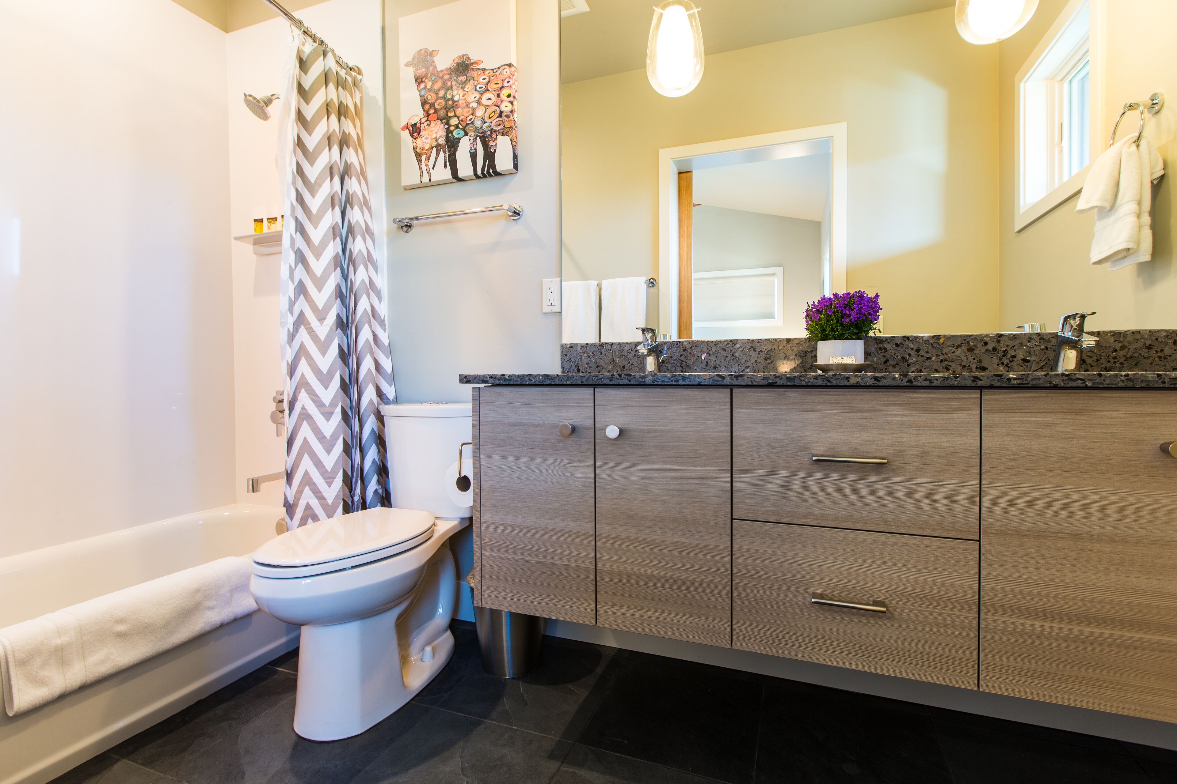 Une salle de bain moderne équipée d’une douche, de toilettes, d’un meuble-lavabo avec des tiroirs et d’un miroir.