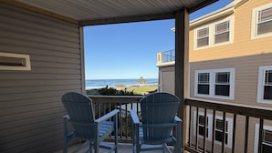 A balcony with two chairs, a view of the ocean, and a beach pavilion. - 2 Bed, 2 Bath Condo with an Oceanfront Pool and Ocean View from the Unit. (Kill Devil Hills)