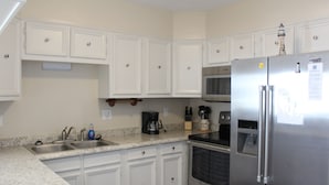 A kitchen with white cabinets, a stainless steel refrigerator, a microwave, and a coffee maker. - 2 Bed, 2 Bath Condo with an Oceanfront Pool and Ocean View from the Unit. (Kill Devil Hills)
