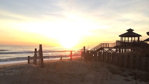 A beach with a wooden walkway leading to a gazebo-like structure. - 2 Bed, 2 Bath Condo with an Oceanfront Pool and Ocean View from the Unit. (Kill Devil Hills)