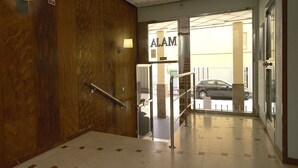 En hotellentrél med en vägg av trä, en skylt med texten ”ALAM” och en bil parkerad utanför.