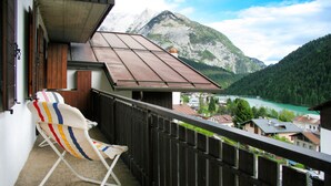 Ein Balkon mit einem Stuhl, Blick auf einen Berg und einen See.