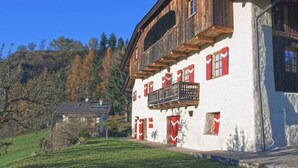 Un chalet traditionnel doté d’un balcon en bois, de murs blancs et de volets rouges.