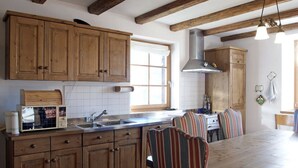 Une cuisine avec des meubles en bois, une cuisinière et des chaises à rayures.