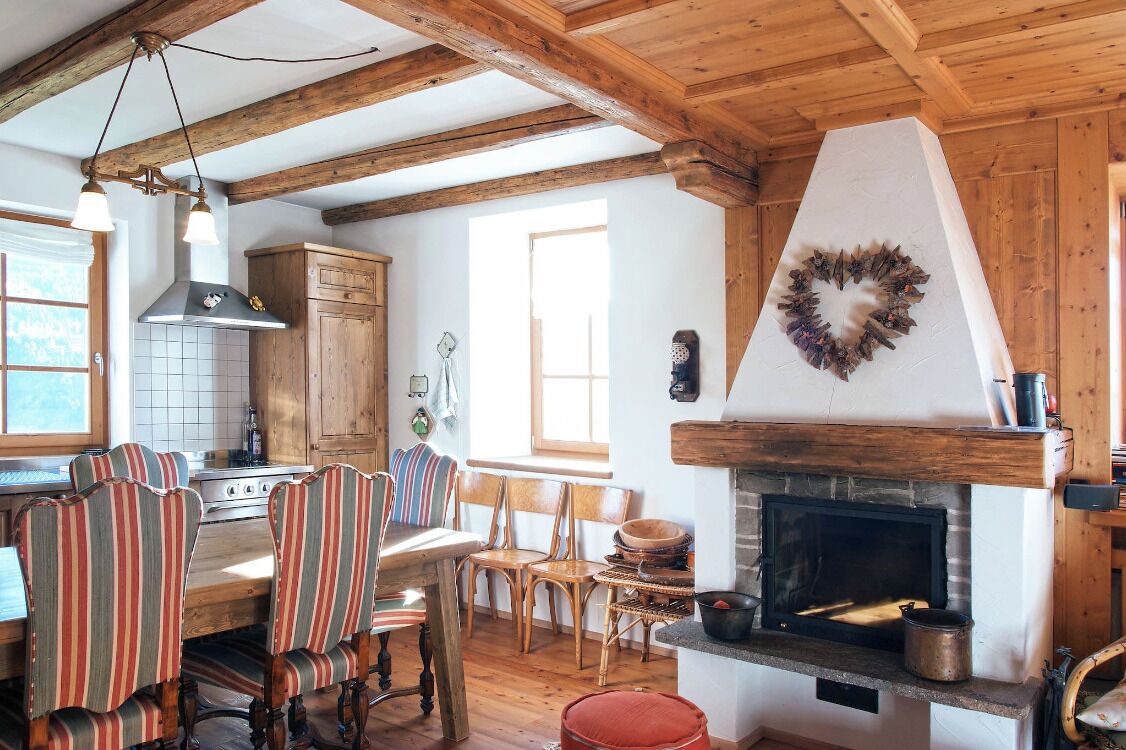 Une cuisine rustique avec des poutres en bois, une cheminée et des chaises à rayures.