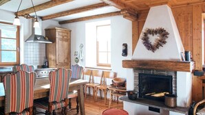 Une cuisine rustique avec des poutres en bois, une cheminée et des chaises à rayures.