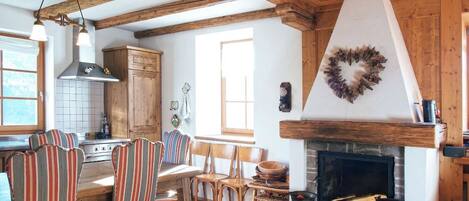 Une cuisine rustique avec des poutres en bois, une cheminée et des chaises à rayures.