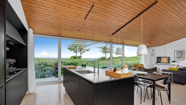 A modern kitchen with a large island, a dining area with chairs, and a view of the outdoors.