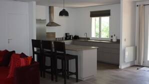 Une cuisine moderne avec un îlot central, des chaises en bois foncé et un luminaire suspendu.