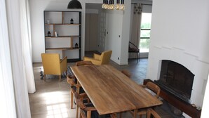 Un vaste espace dédié à la salle à manger, avec une longue table en bois et de nombreuses chaises, une bibliothèque intégrée et une cheminée.