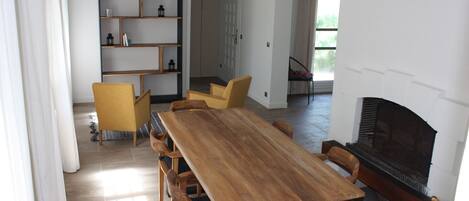 A spacious dining area with a long wooden table and multiple chairs, a built-in bookshelf, and a fireplace.