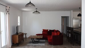 Un salon moderne avec un canapé rouge, une table basse en bois et des lampes suspendues.
