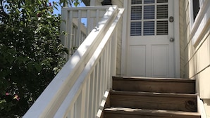 Una escalera de madera con barandillas blancas que conduce a una puerta blanca con un ventanal.