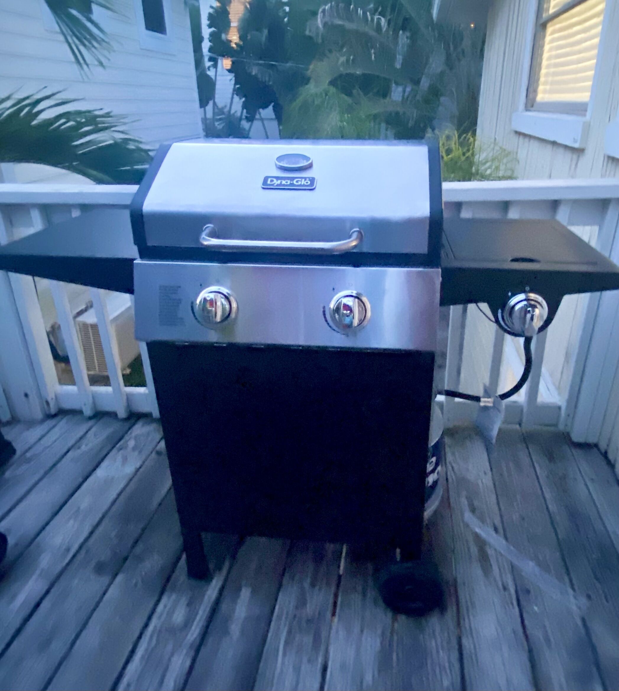 Een draagbare grill met bedieningspaneel en een extra brander, geplaatst op een houten terras.