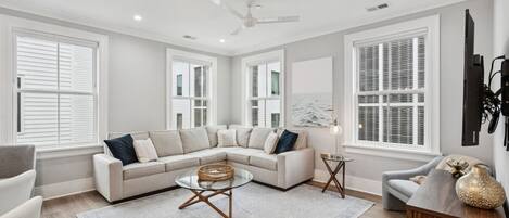 A spacious living room with a large L-shaped sectional sofa, a glass coffee table, and a small side table.