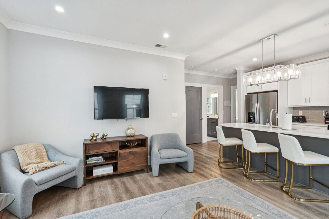 Un salon moderne avec un téléviseur à écran plat, un meuble de rangement en bois et un canapé gris.