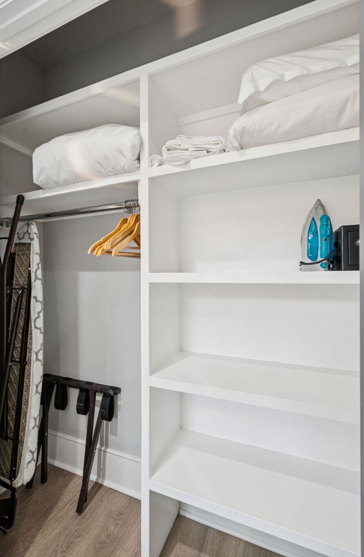 A closet with shelves, a hanging rack, and a folded bed.