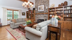 Una sala de estar acogedora con chimenea de piedra, estanterías de madera y un candelabro.