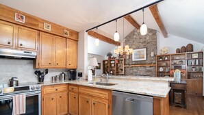 Una cocina con armarios de madera, horno empotrado, lavavajillas y una pared de acento de piedra.