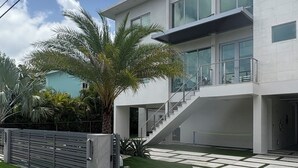 Ein modernes, zweistöckiges Haus mit Balkon, Treppe und gepflegtem Rasen.