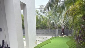 Ein gepflegter, künstlicher Rasen mit einem Putting Green und Golfschlägern.