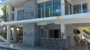 Ein modernes mehrgeschossiges Gebäude mit Pool, Außenbar und einer Treppe, die zu einem Balkon führt.