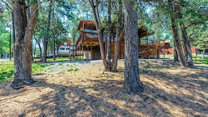 A cabin with a wooden deck and stairs leading to a covered area.