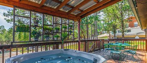 A hot tub under a wooden pergola with a view of trees and a parked RV.