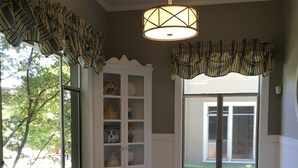 A dining area with a wooden table, striped table runner, and a hanging light fixture. - Stunning, Large, Beautifully Decorated Home in Downtown Lodi with Spa Amenities  (Lodi)