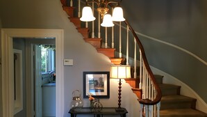 A staircase with wooden railings and a chandelier. There is a framed picture on the wall and a small table with a vase and a bicycle. - Stunning, Large, Beautifully Decorated Home in Downtown Lodi with Spa Amenities  (Lodi)